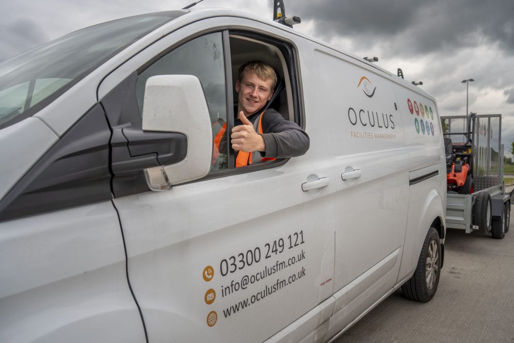 A staff member giving a thumbs up in a white branded Oculus FM van.