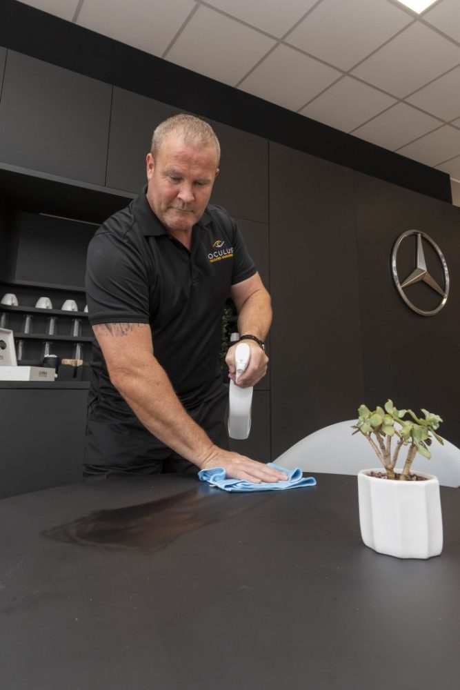 A cleaning professional wiping down a hard surface.