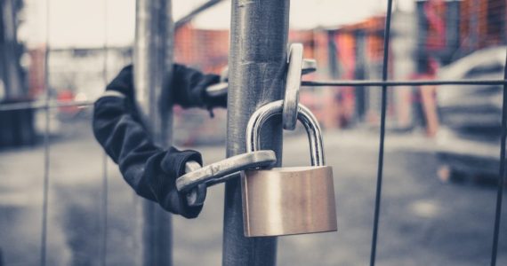 An effective padlock is securely attached to a fence in a construction site.