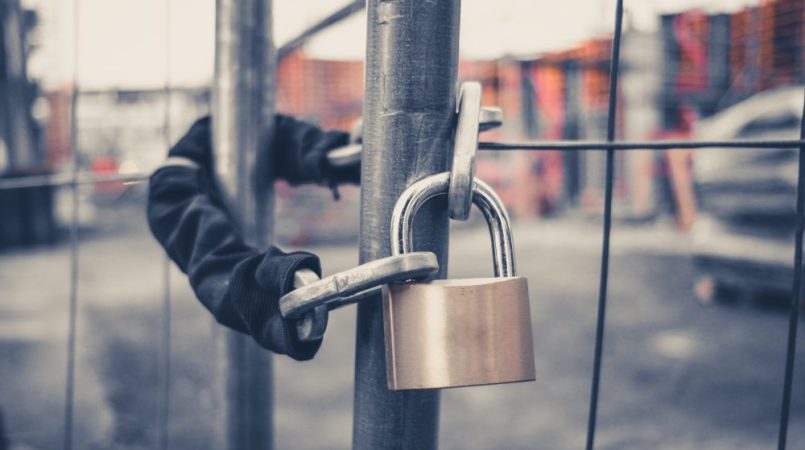 An effective padlock is securely attached to a fence in a construction site.
